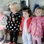 toddler girls lined up against wall outdoors